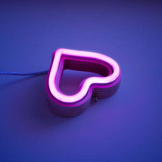 Close-up angled view of magenta neon heart ornament showing handcrafted layered wood frame and LED neon tubing construction by Our Glowing Hearts
