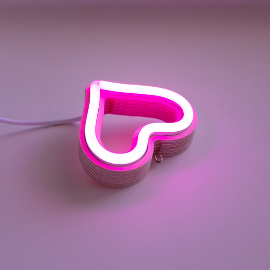 Close-up angled view of pink neon heart ornament showing handcrafted layered wood frame and LED neon tubing construction by Our Glowing Hearts
