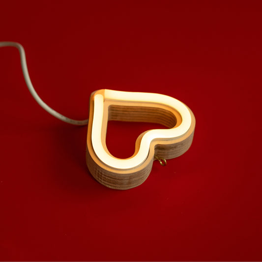 Close-up angled view of warm white neon heart ornament showing handcrafted layered wood frame and LED neon tubing construction by Our Glowing Hearts
