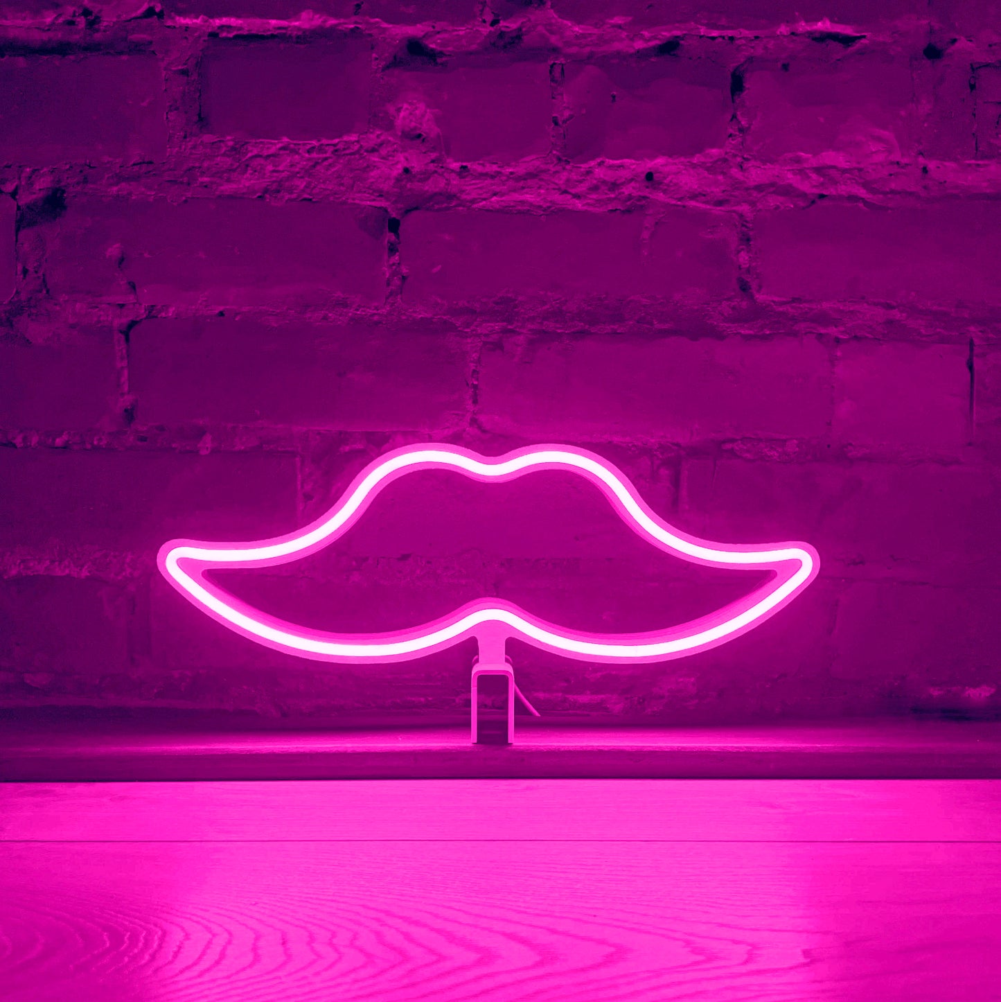 Pink neon moustache art glowing against a brick wall - Movember LED neon moustache light by Our Glowing Hearts handmade in Canada