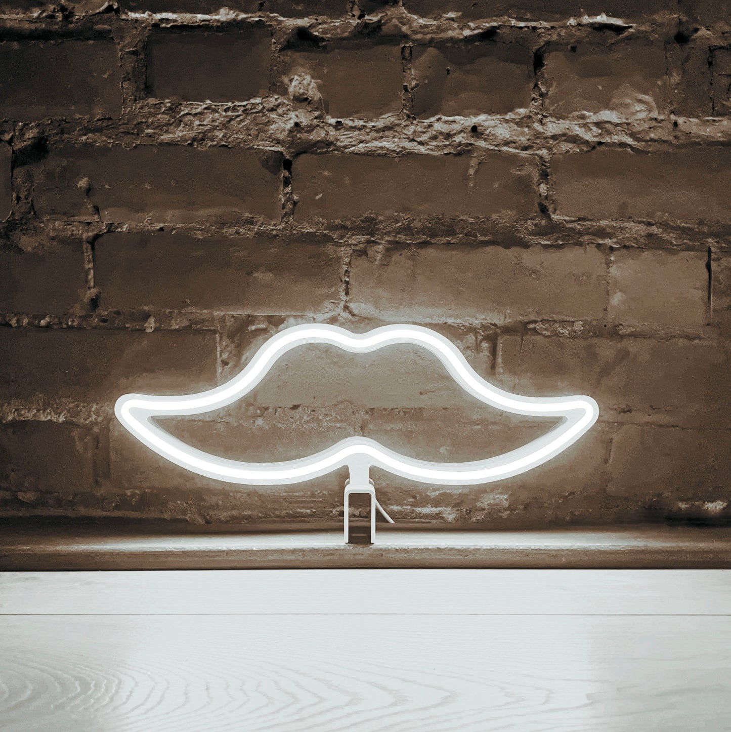Cool white neon moustache art glowing against a brick wall - Movember LED neon moustache light by Our Glowing Hearts handmade in Canada