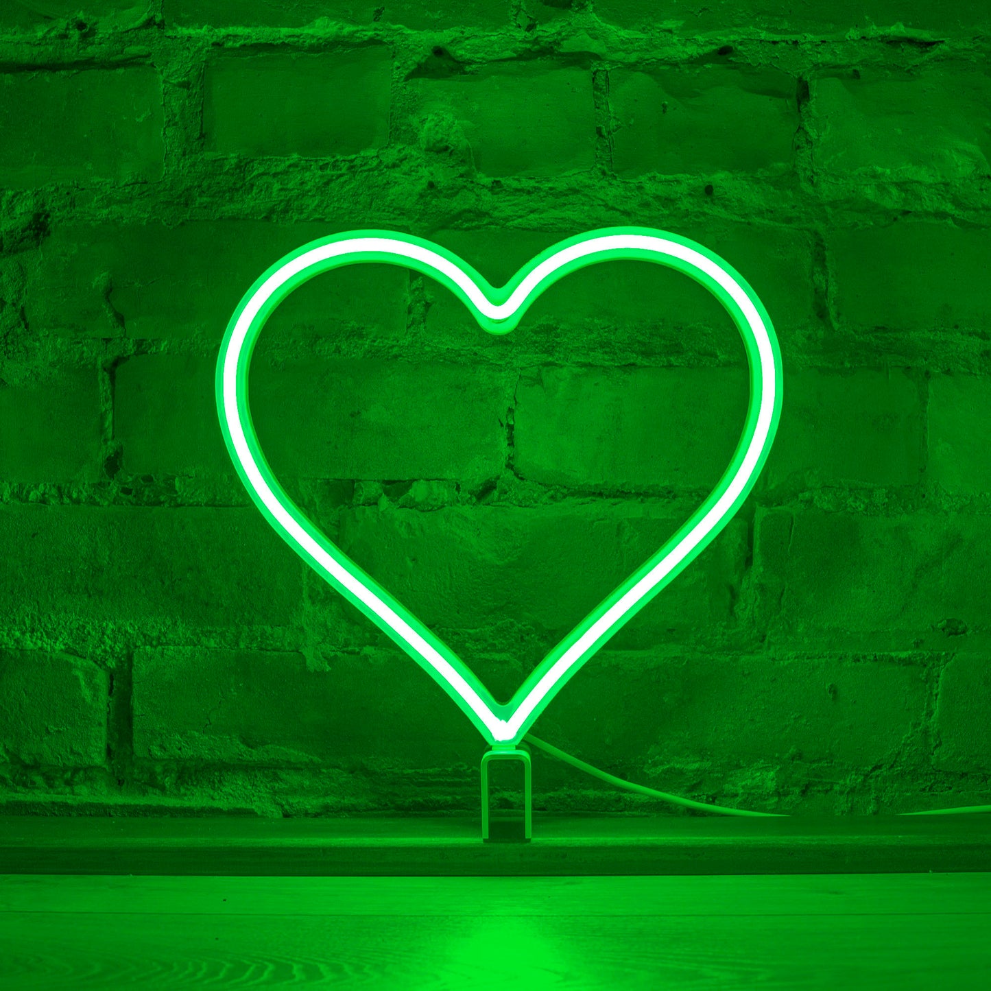 Green neon heart art glowing against a brick wall - 12 inch LED neon heart light by Our Glowing Hearts, handmade in Canada