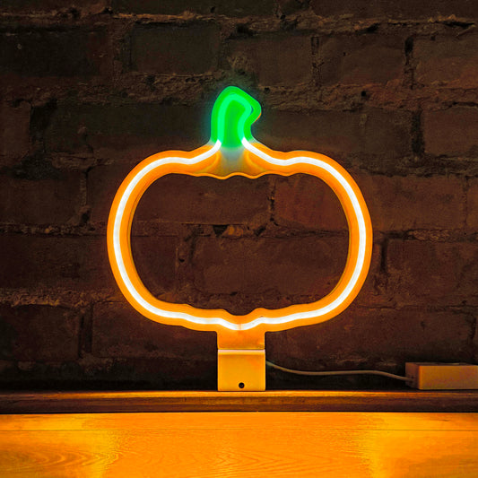 The Glowing Pumpkin neon art in orange and green glowing against a brick wall - LED neon pumpkin light for Halloween and autumn decor by Our Glowing Hearts handmade in Canada