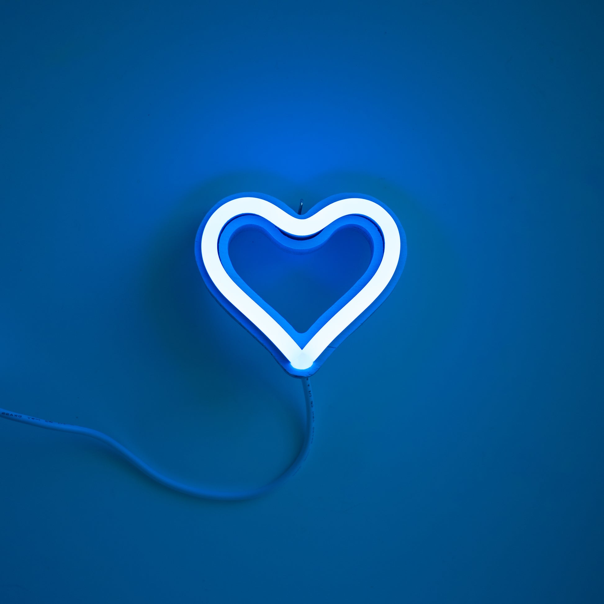 Cyan neon heart ornament art glowing against a blue background - 3 inch LED neon heart light by Our Glowing Hearts handmade in Canada