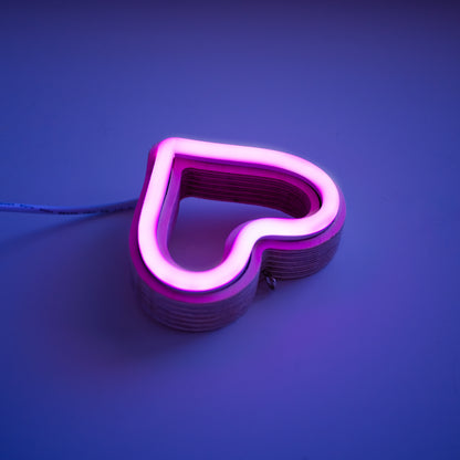 Close-up angled view of magenta neon heart ornament showing handcrafted layered wood frame and LED neon tubing construction by Our Glowing Hearts