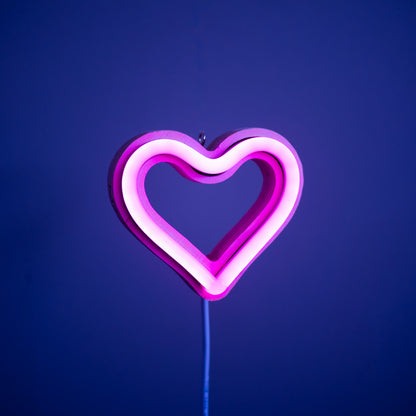 Front view of magenta neon heart ornament with hanging hook glowing against a blue background - 3 inch LED neon heart light by Our Glowing Hearts