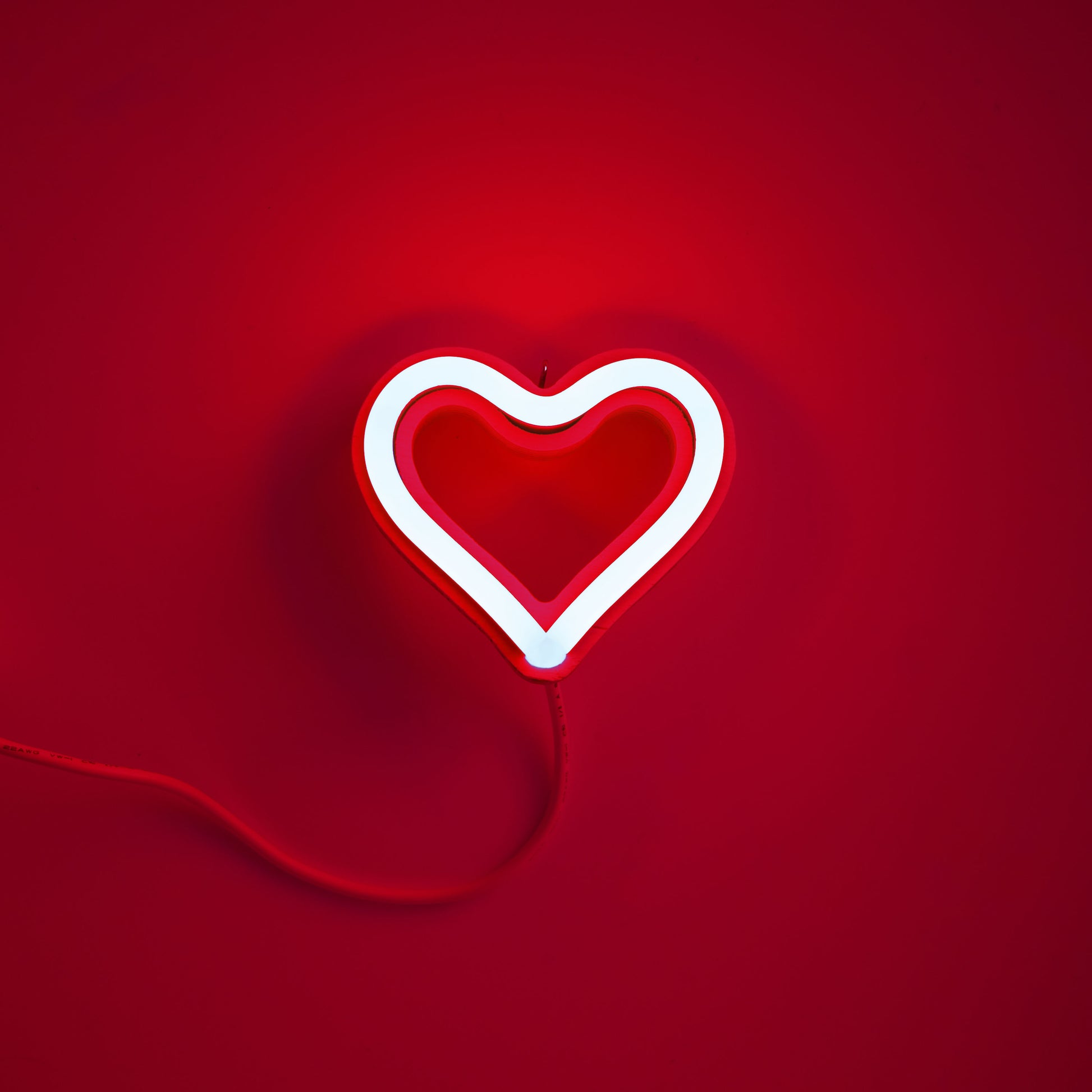 Red neon heart ornament glowing on red background - 3.5 inch LED neon ornament by Our Glowing Hearts handmade in Canada