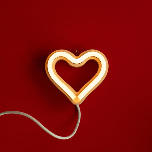 Warm white neon heart ornament art glowing against a red background - 3 inch LED neon heart light by Our Glowing Hearts handmade in Canada