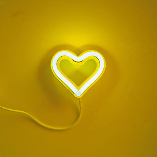 Yellow neon heart ornament glowing on yellow background - 3.5 inch LED neon ornament by Our Glowing Hearts handmade in Canada