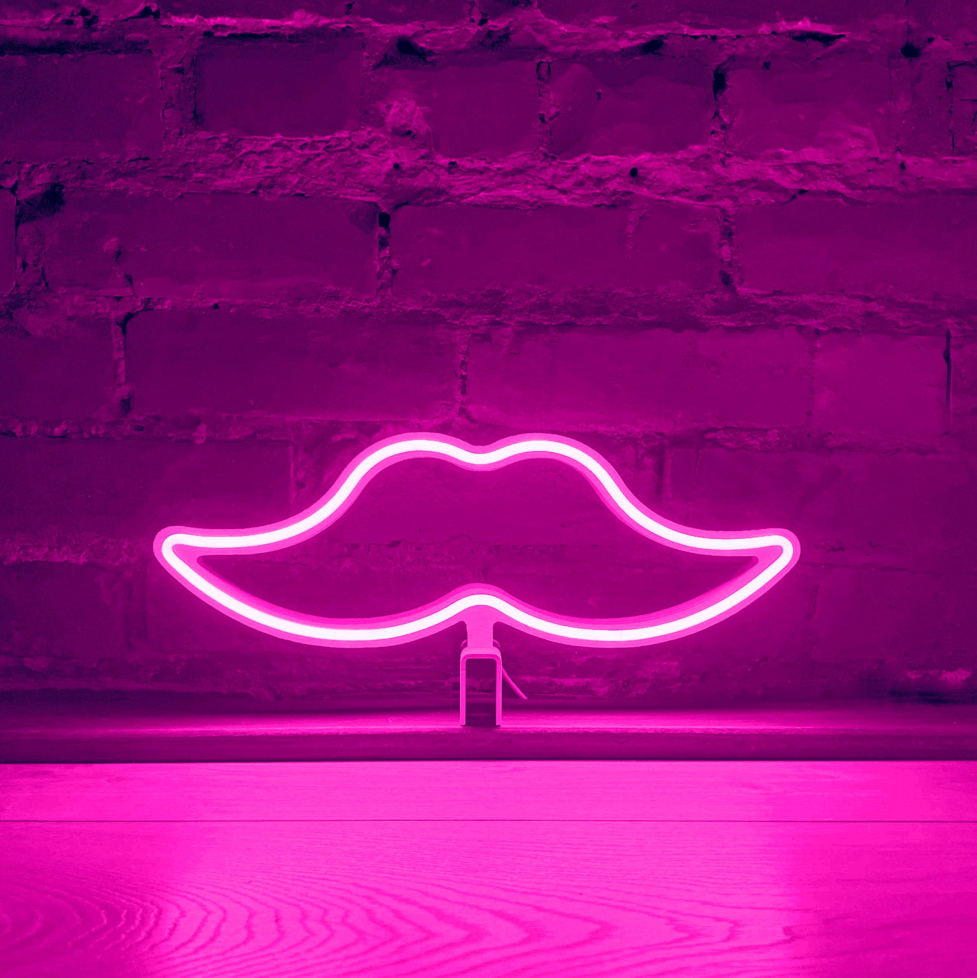 Pink neon moustache art glowing against a brick wall - Movember LED neon moustache light by Our Glowing Hearts handmade in Canada