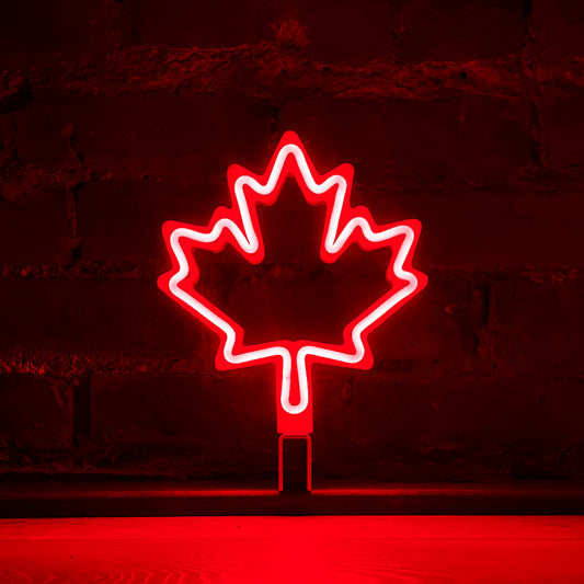 Red neon maple leaf art glowing against a brick wall - LED neon maple leaf light by Our Glowing Hearts handmade in Canada