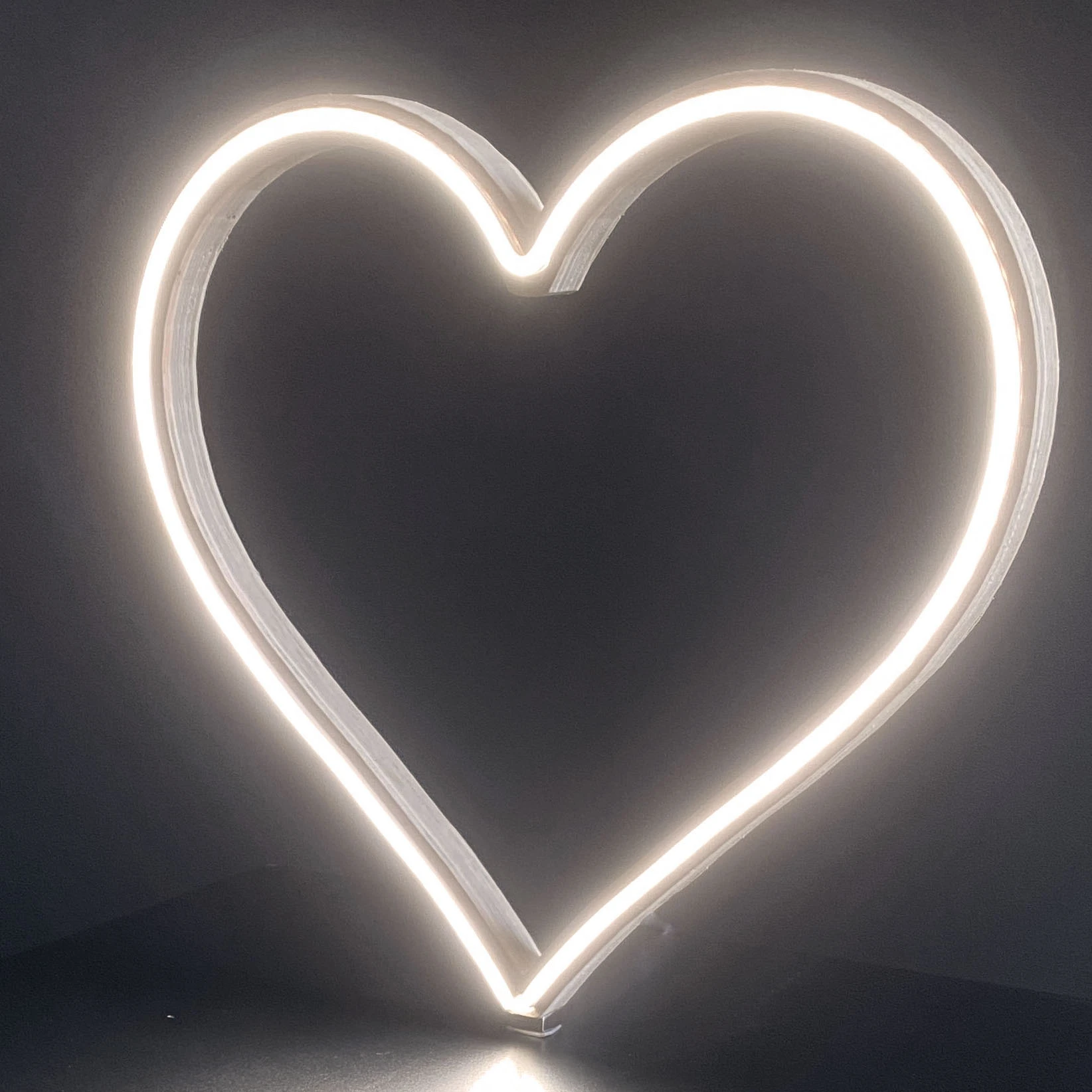 Cool white neon heart art glowing brightly against a dark background - front view of 12 inch LED neon heart light showing warm white glow by Our Glowing Hearts