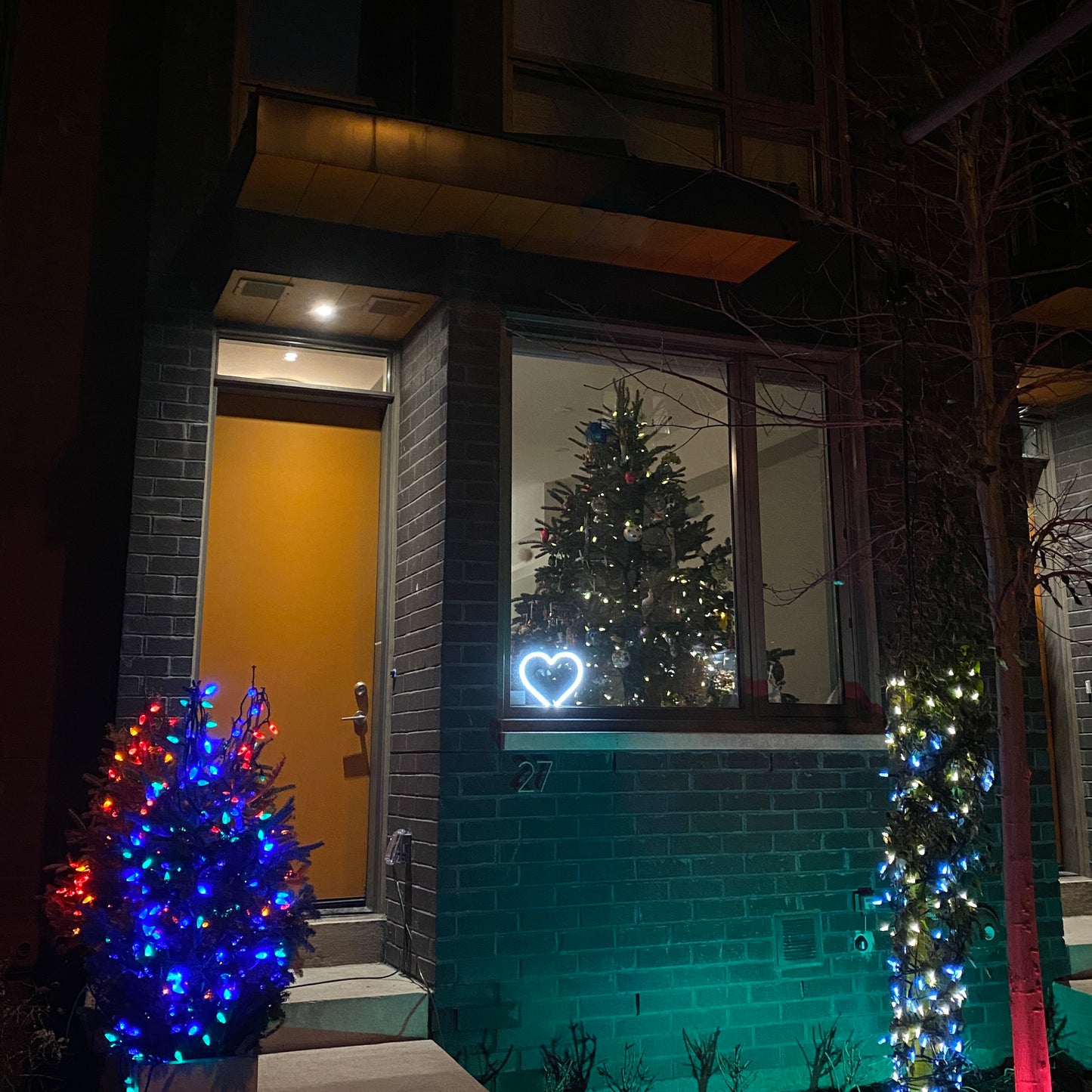 Cool white neon heart art glowing in a front window surrounded by festive Christmas lights and holiday decorations - LED neon heart perfect for seasonal window display by Our Glowing Hearts