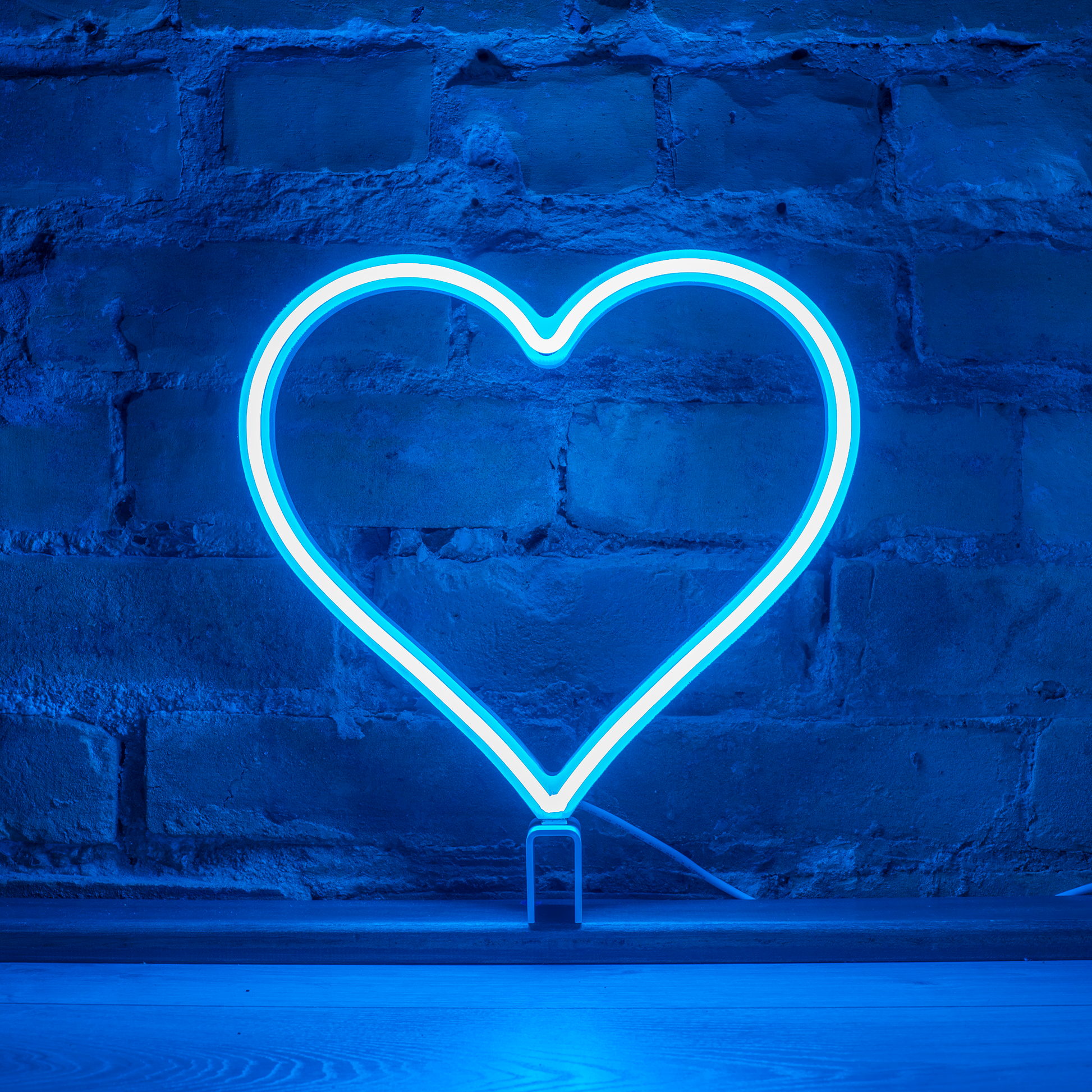 Cyan neon heart art glowing against a brick wall - 12 inch LED neon heart light by Our Glowing Hearts, handmade in Canada