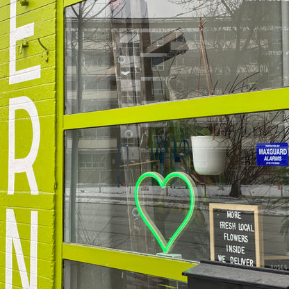 Green neon heart art displayed in a storefront window of a local flower shop - LED neon heart window decor for small businesses by Our Glowing Hearts, handmade in Canada
