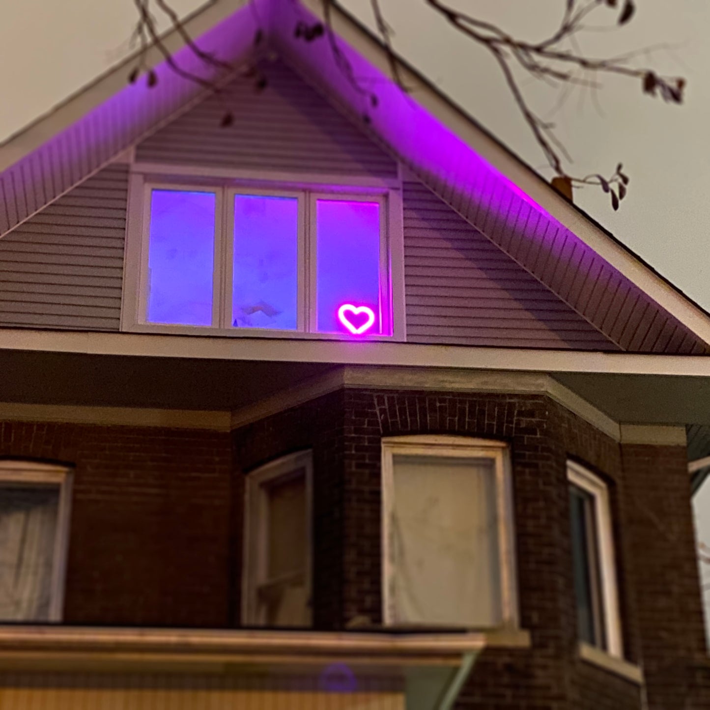 Magenta neon heart art glowing in a home window at night - LED heart-shaped light visible from outside, perfect for window decor and spreading love in the community