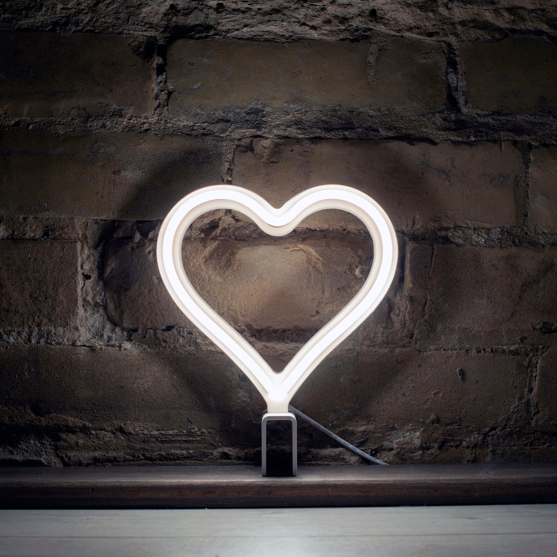 Mini cool white neon heart art glowing against a brick wall - 7 inch LED neon heart light by Our Glowing Hearts handmade in Canada