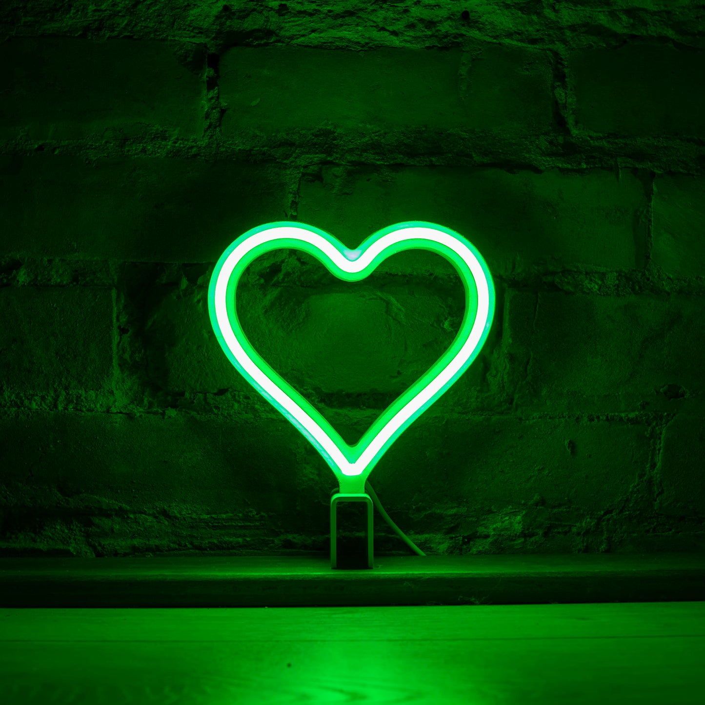 Mini green neon heart art glowing against a brick wall - 7 inch LED neon heart light by Our Glowing Hearts handmade in Canada