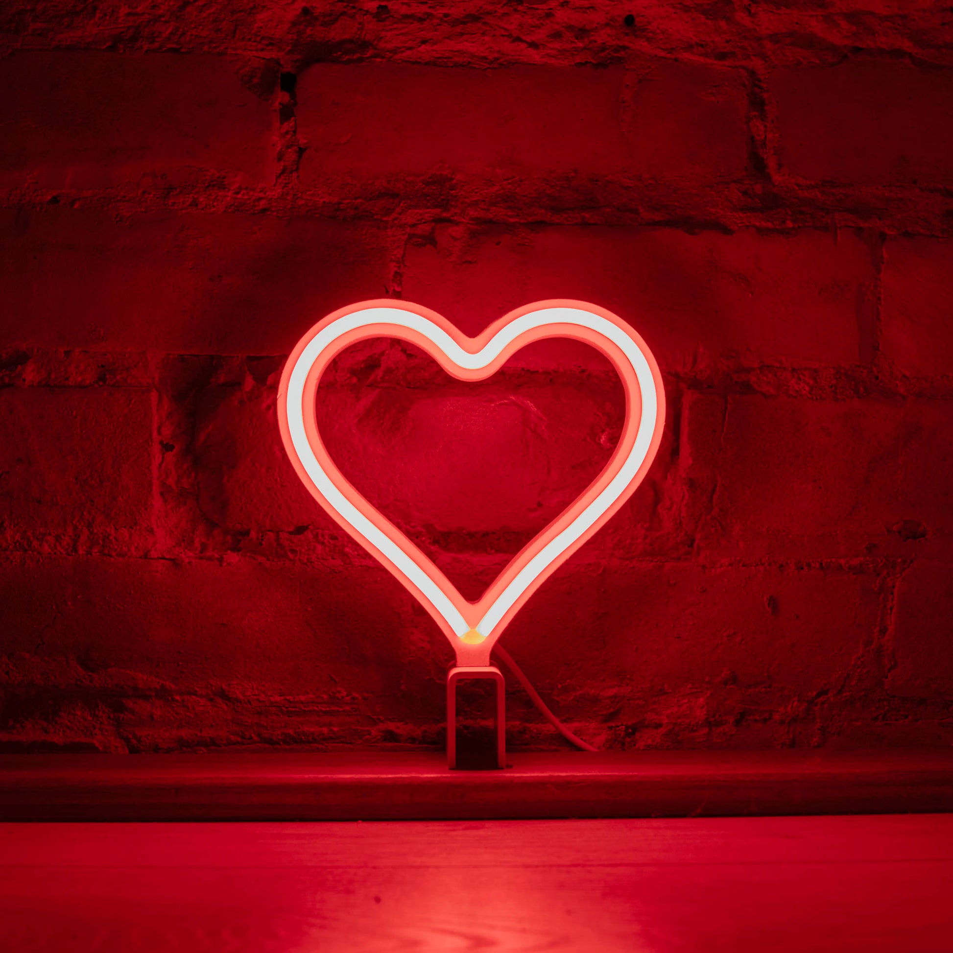 Mini red neon heart art glowing against a brick wall - 7 inch LED neon heart light by Our Glowing Hearts handmade in Canada