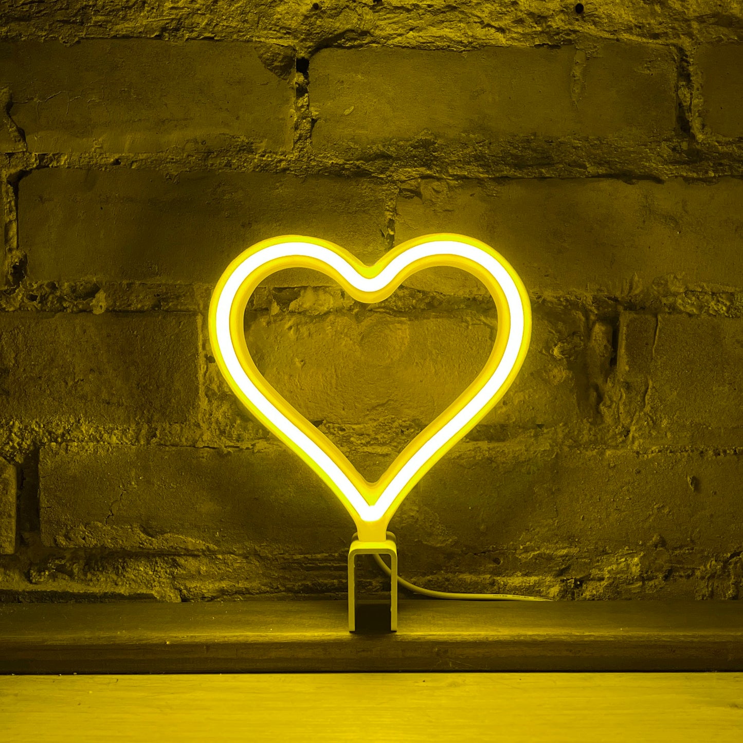 Mini yellow neon heart art glowing against a brick wall - 7 inch LED neon heart light by Our Glowing Hearts handmade in Canada