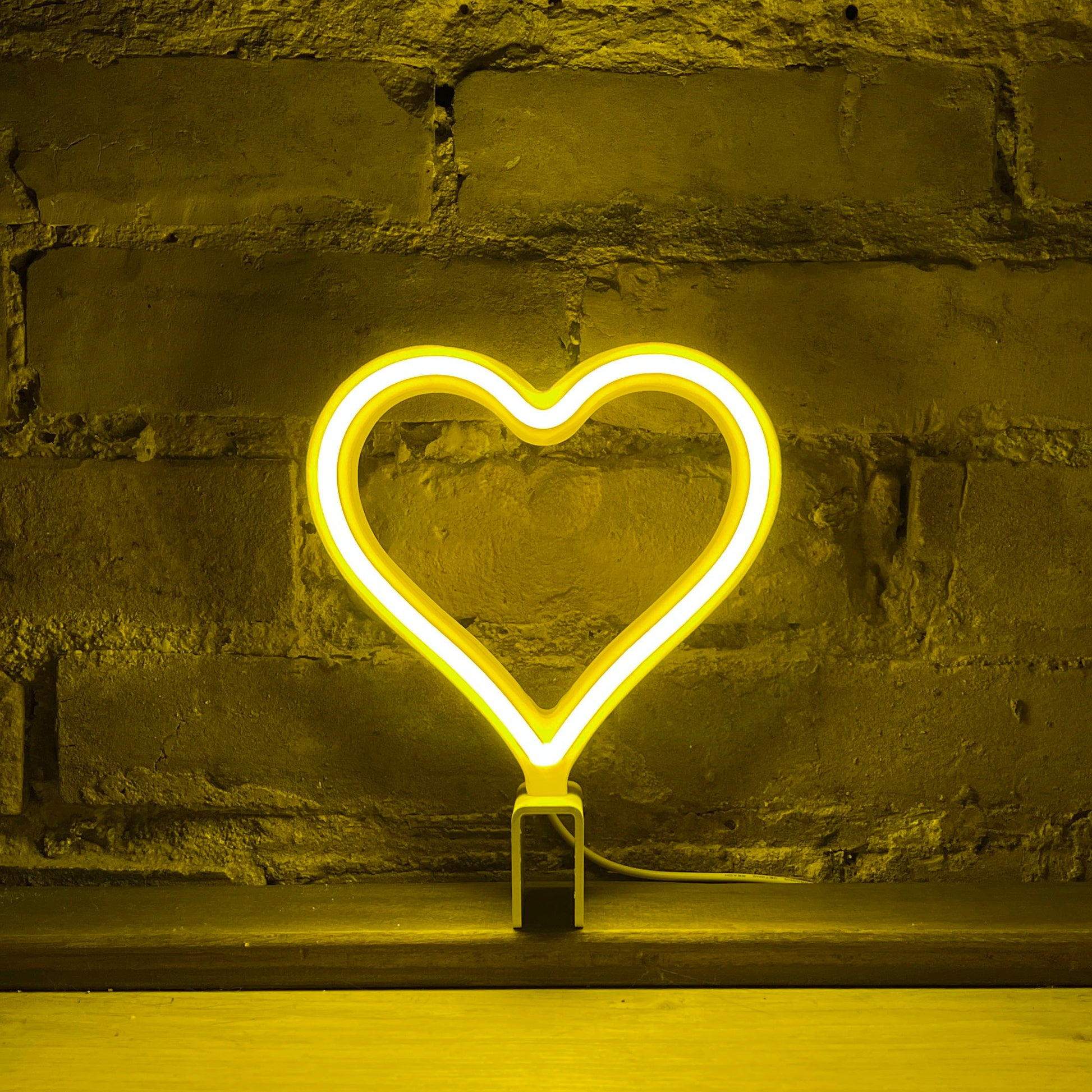 Mini yellow neon heart art glowing against a brick wall - 7 inch LED neon heart light by Our Glowing Hearts handmade in Canada