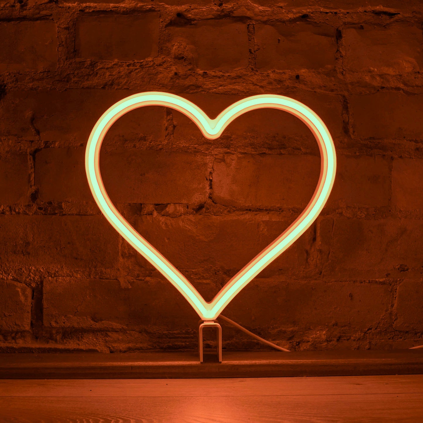 Orange neon heart art glowing against a brick wall - 12 inch LED neon heart light by Our Glowing Hearts, handmade in Canada