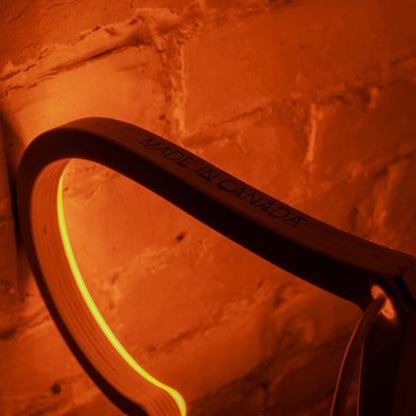 Close-up of orange neon heart art wood frame with Made in Canada engraving against a brick wall - handcrafted LED neon heart detail by Our Glowing Hearts