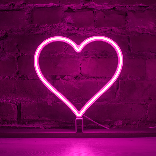 Pink neon heart art glowing against a brick wall - 12 inch LED neon heart light by Our Glowing Hearts, handmade in Canada