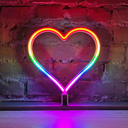 Our Glowing Hearts Signature Rainbow neon heart art glowing against a brick wall - 12 inch LED rainbow heart light with animated color cascade, handmade in Canada